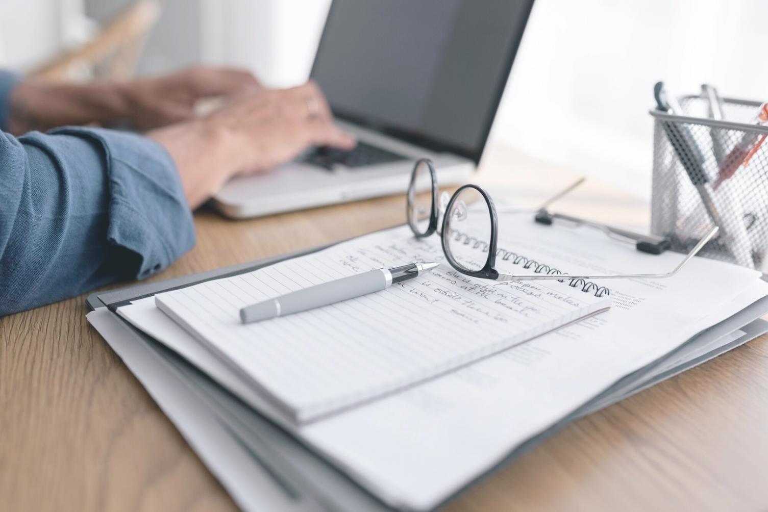 Espace de travail équipé pour formation en ligne avec ordinateur portable, casque audio et documents financiers